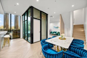 Enjoy meals in the dining area with a marble table and blue chairs, and step outside to a green oasis through the sliding glass door.