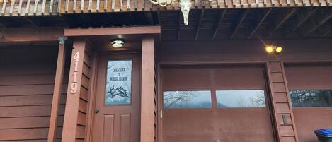 Ein hölzernes Gebäude mit Balkon, einem Willkommensschild und einem Hund davor.