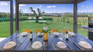 An outdoor dining area with a view of a pool and landscape.