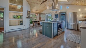 A spacious kitchen with a central island, stainless steel appliances, and a wooden ceiling.