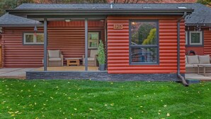 A log cabin with a porch, number 125, featuring two sofas and a potted plant.