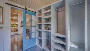 A walk-in closet with open shelving, a sliding door, and a view into the adjacent dining area.