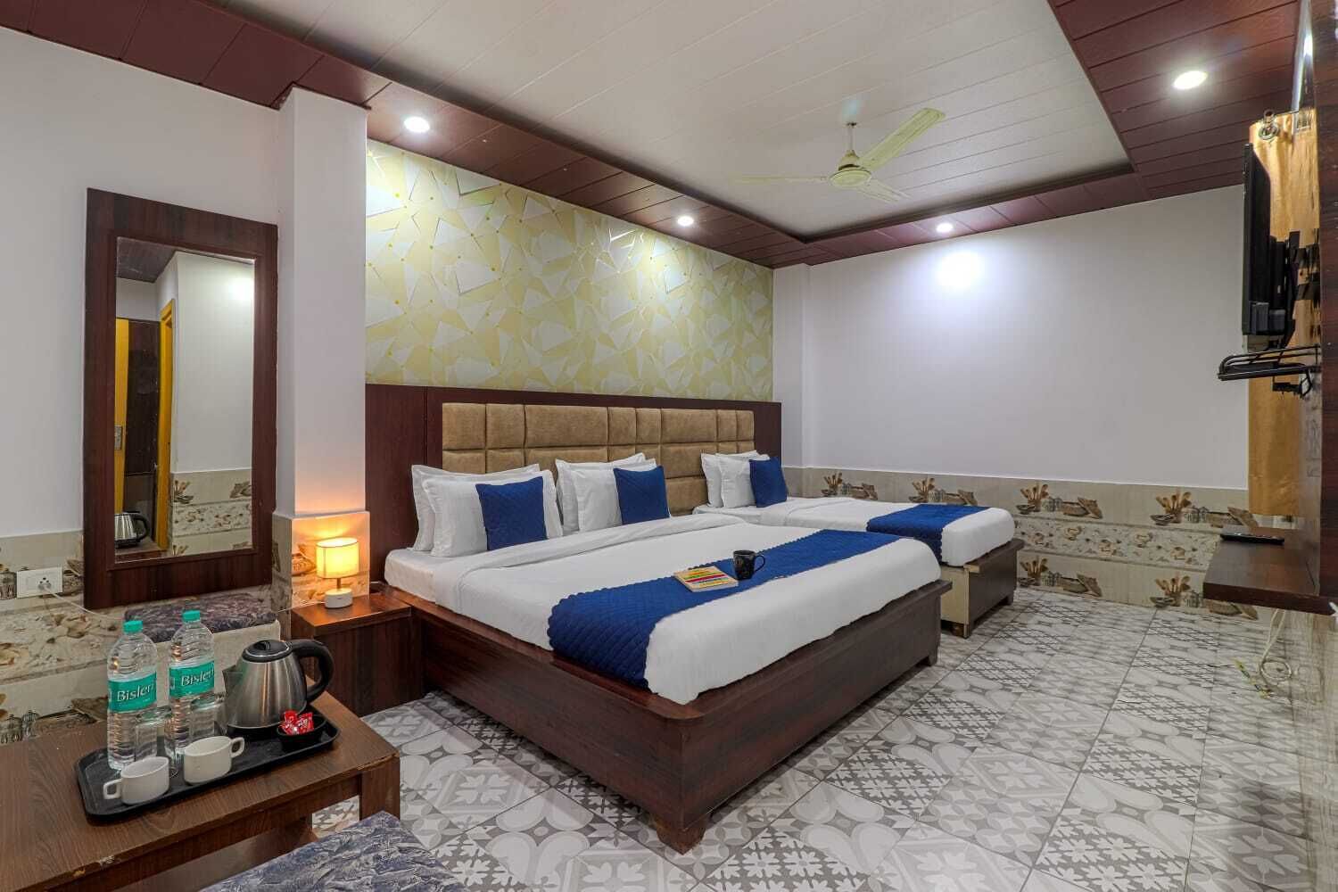 A hotel room with a large bed, bedside tables, a mirror, and a ceiling fan.