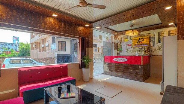 A hotel reception area with a red sofa, a reception desk, and a ceiling fan.