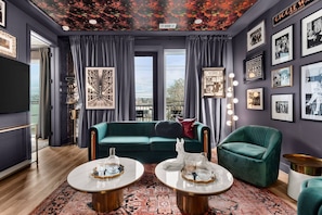 Uma sala de estar moderna com um sofá verde, duas mesas de centro e um tapete estampado.