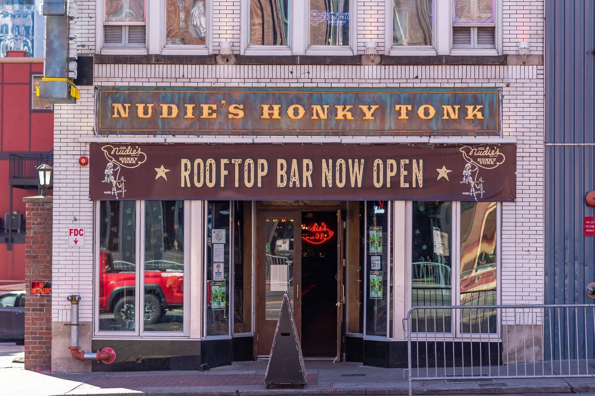 A storefront with a sign reading 'Nudie's Honky Tonk' and 'Rooftop Bar Now Open.'