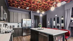 Une cuisine moderne dotée d’un îlot central, d’appareils électrom énagers en acier inoxydable et d’un plafond décoratif.