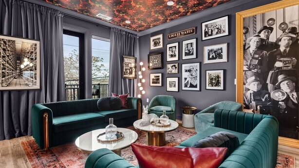 Un salon moderne avec un canapé vert, une table basse ronde et un grand mur recouvert de photographies encadrées.