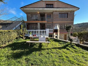 A two-story house with a balcony, a stone oven, and a staircase leading to the upper floor.