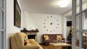 Una sala de estar con un sofá beige, un sofá marrón, una mesa de centro, una chimenea y un reloj de pared.