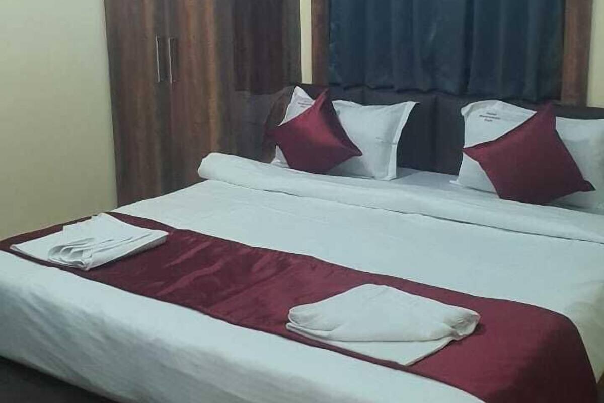 A hotel room with a bed, wooden wardrobe, and a ceiling with blue lighting.