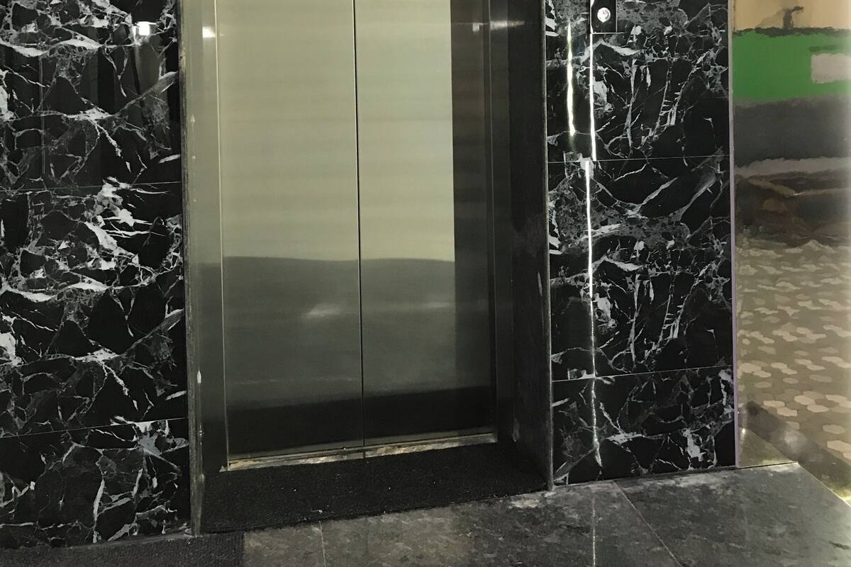 An elevator with a digital display showing the number 3, surrounded by black marble walls.