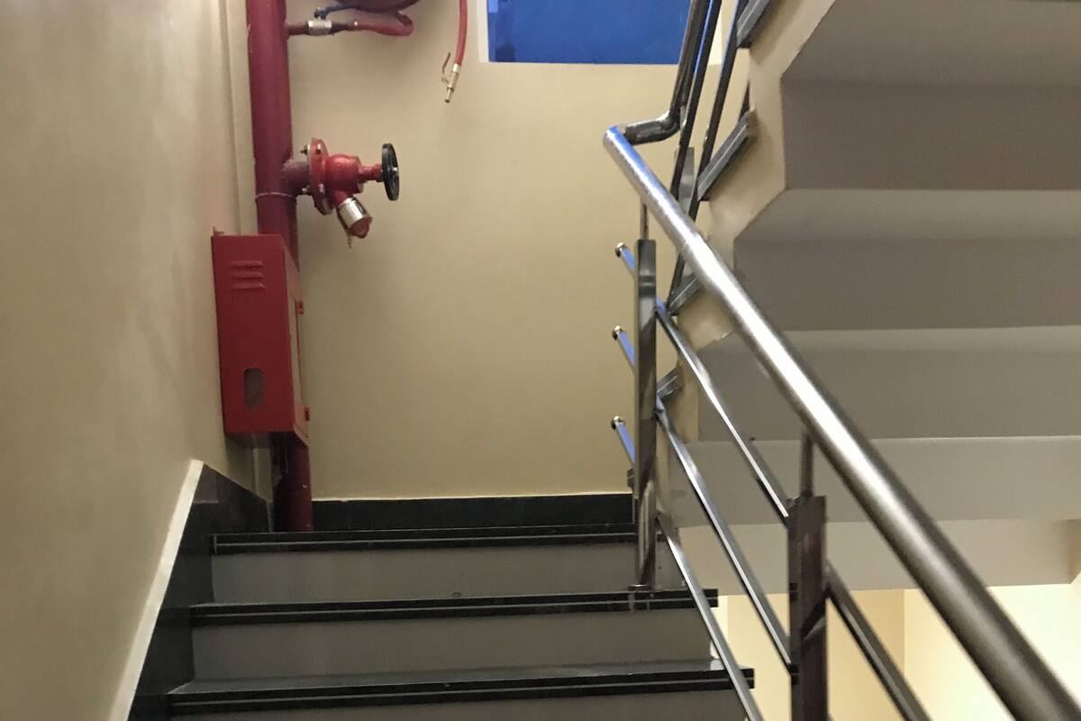 A staircase with metal railings and a red fire extinguisher mounted on the wall.