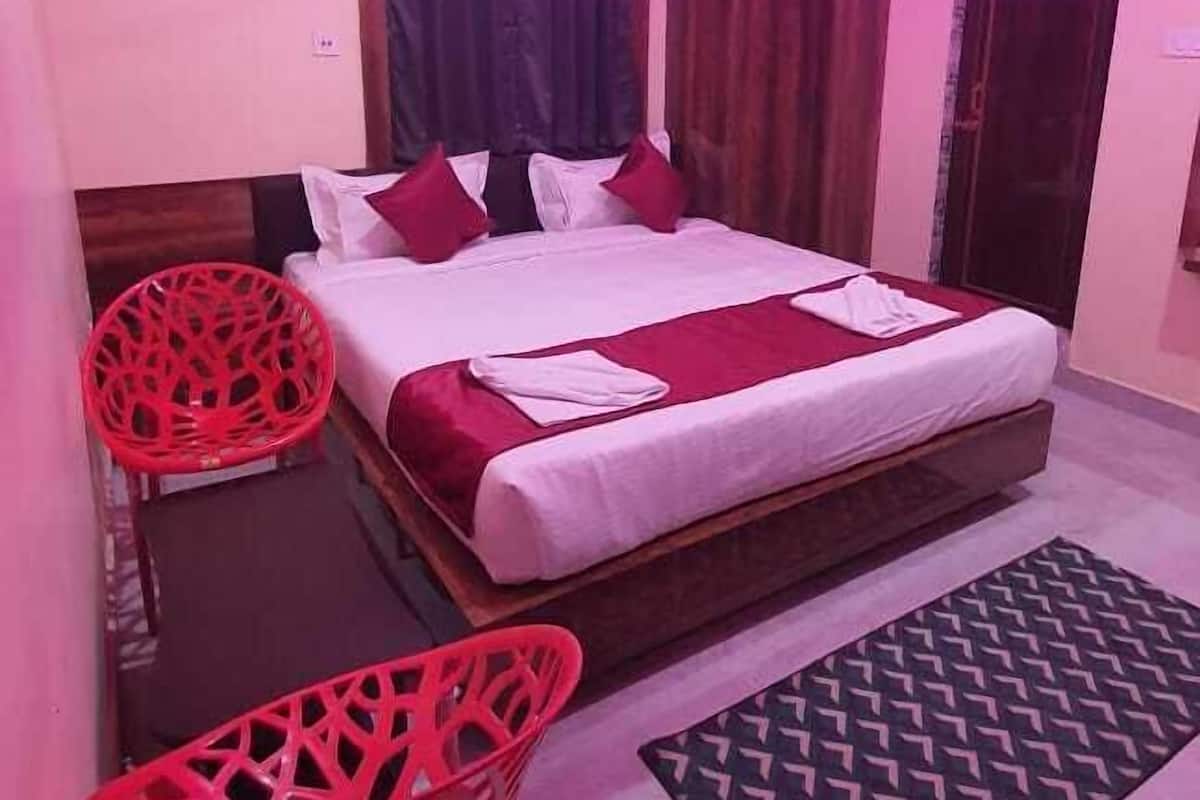 A bedroom with a bed, a ceiling fan, a red chair, and a patterned rug.