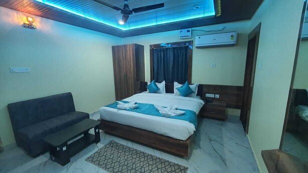 A bedroom with a bed, a sofa, a coffee table, and a ceiling fan. - Hotel Swarna Lata (Puri)