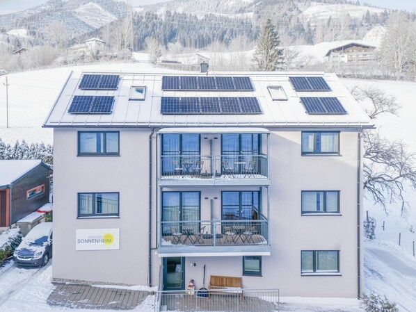 A modern building with multiple balconies and solar panels on the roof.