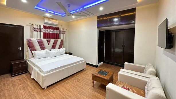 A bedroom with a bed, a desk, a chair, a wardrobe, and a ceiling with recessed lighting. - Serene Inn F10 (Islamabad)