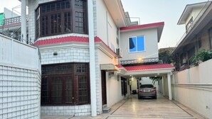 A two-story building with a covered driveway and a parked car. - Serene Inn F10 (Islamabad)