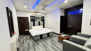 A modern bedroom with a bed, a ceiling fan, a wardrobe, and a seating area. - Serene Inn F10 (Islamabad)