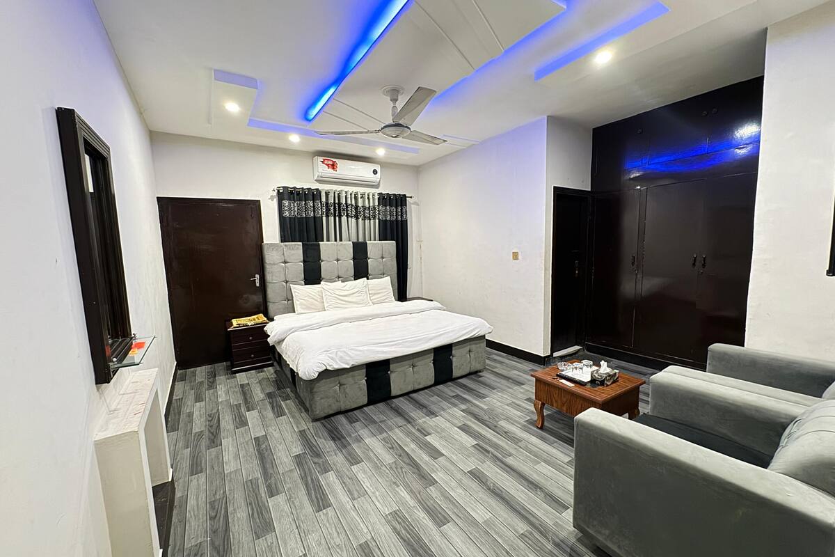 A modern bedroom with a bed, a ceiling fan, a wardrobe, and a seating area.