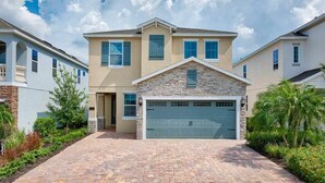 A two-story house with a stone facade, a garage, and a brick driveway.