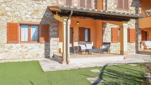 Un bâtiment en pierre doté d’un patio couvert aménagé avec du mobilier d’extérieur.