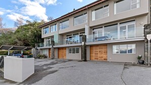 Un immeuble résidentiel à plusieurs étages, doté d’un garage, d’une allée couverte et d’un balcon avec espace salon extérieur.