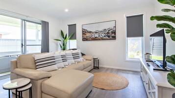 A modern living room with a sofa, a round rug, and a large window.