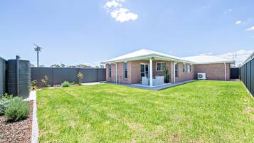 A single-story brick house with a covered patio and a fenced backyard.