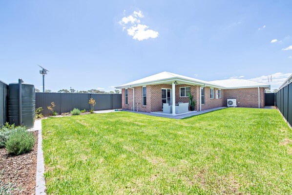 A single-story brick house with a covered patio and a fenced backyard. - Villa Magnolia (Dubbo)