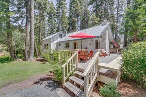 Een chalet met een terras, buitenmeubels en een rode parasol.
