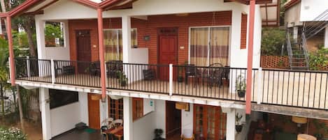 Un edificio de dos pisos con un balcón, un comedor y un pequeño espacio de asientos al aire libre.