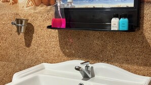 A bathroom with a sink, a mirror, and a shelf with toiletries. - Tera Ella Boutique Hotel by SANS (Ella)