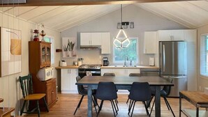 Een moderne keuken met witte kasten, een houten eettafel en een hanglamp.