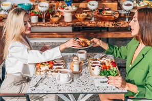 Uma mesa de jantar com diversos alimentos, bebidas, uma cafeteira e um prato de pão.