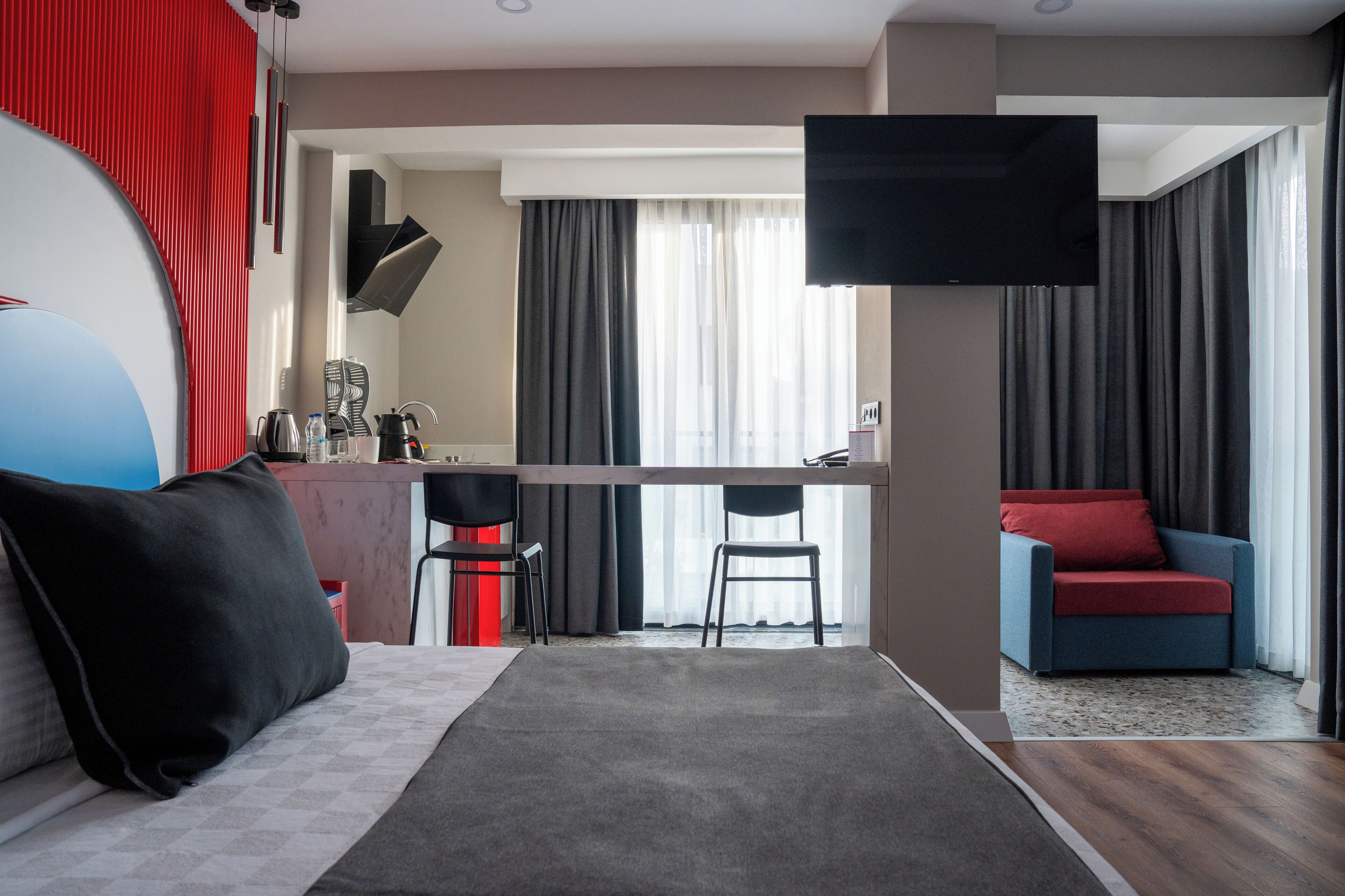 Una habitación de hotel moderna con sofá, zona de comedor y televisor.
