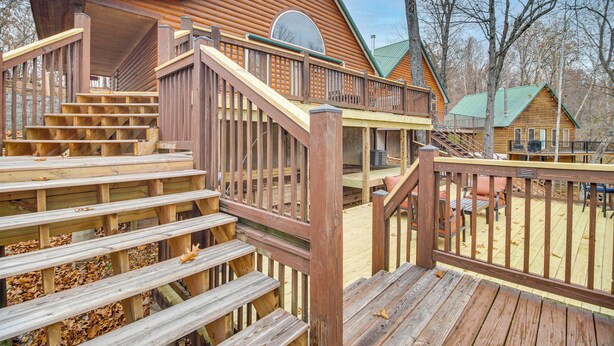 Una cabaña de madera con terraza, escaleras y un porche cubierto.