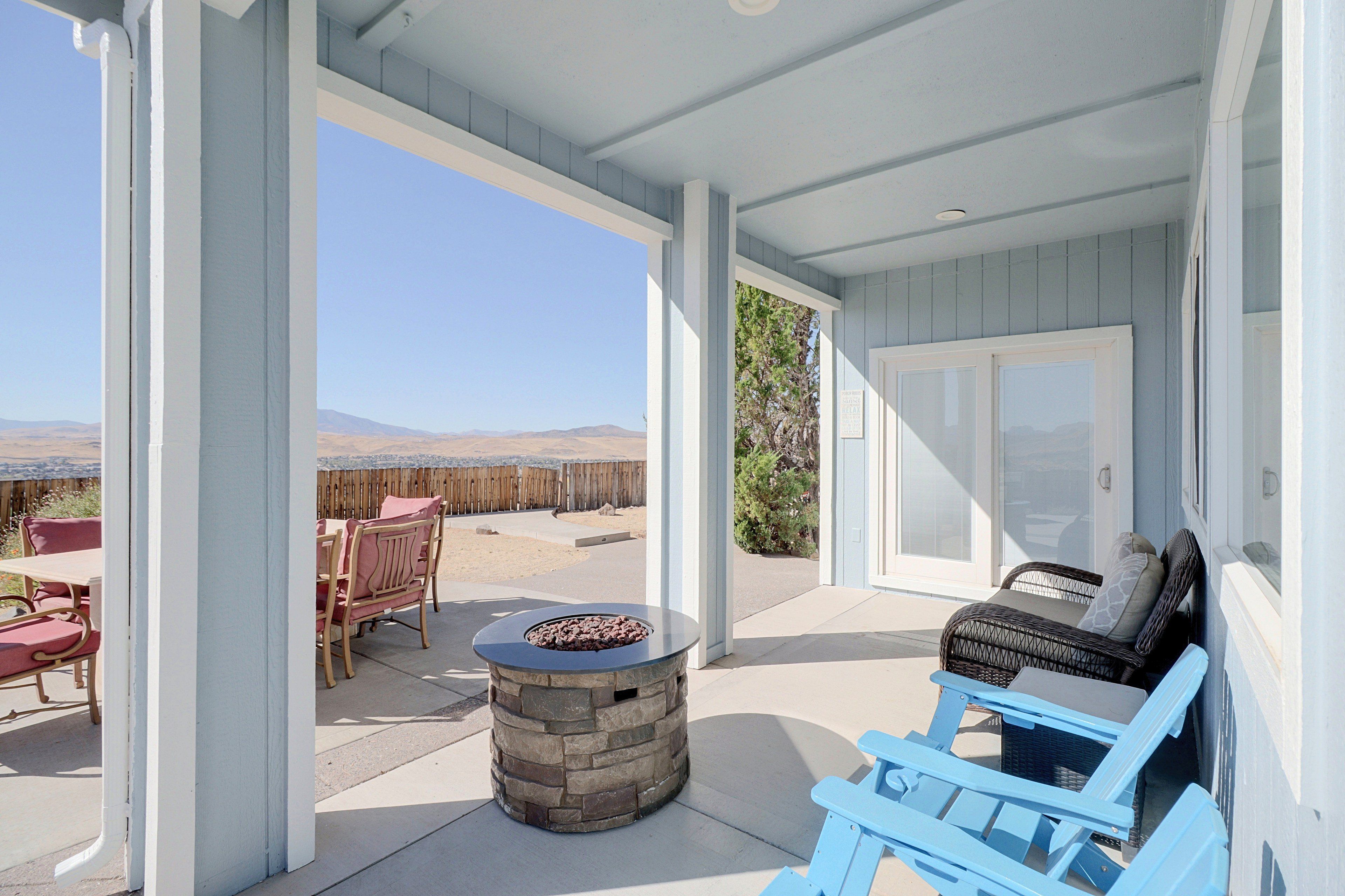 Un patio techado con mobiliario exterior, una chimenea de piedra y vistas al paisaje desértico.