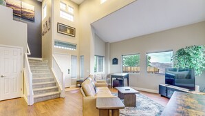 Ein geräumiger Wohnbereich mit Treppe, einer Couch, einem Couchtisch und einem Fernseher.
