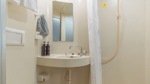 Een badkamer met een wastafel, spiegel, handdoekhouder en douchegordijn.