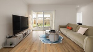 En moderne stue med et fladskærms-tv, en sofa og et sofabord.