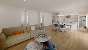 En moderne stue med sofa, sofabord og spiseplads med stole.