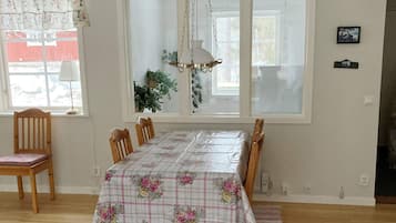 Un comedor con una mesa cubierta con mantel estampado, sillas de madera y una lámpara colgante.