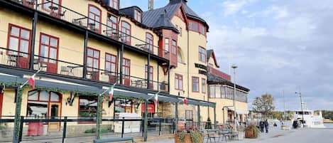 A waterfront hotel with multiple balconies, outdoor seating, and a bar.