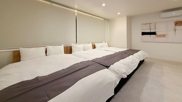 Ein modernes Hotelzimmer mit einem großen Bett, einem Kopfteil und einer Wand-Klimaanlage.