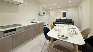 Eine moderne Küche mit Essbereich, darunter ein weiß gedeckter Tisch für vier Personen, eine Couch und eine Mikrowelle.