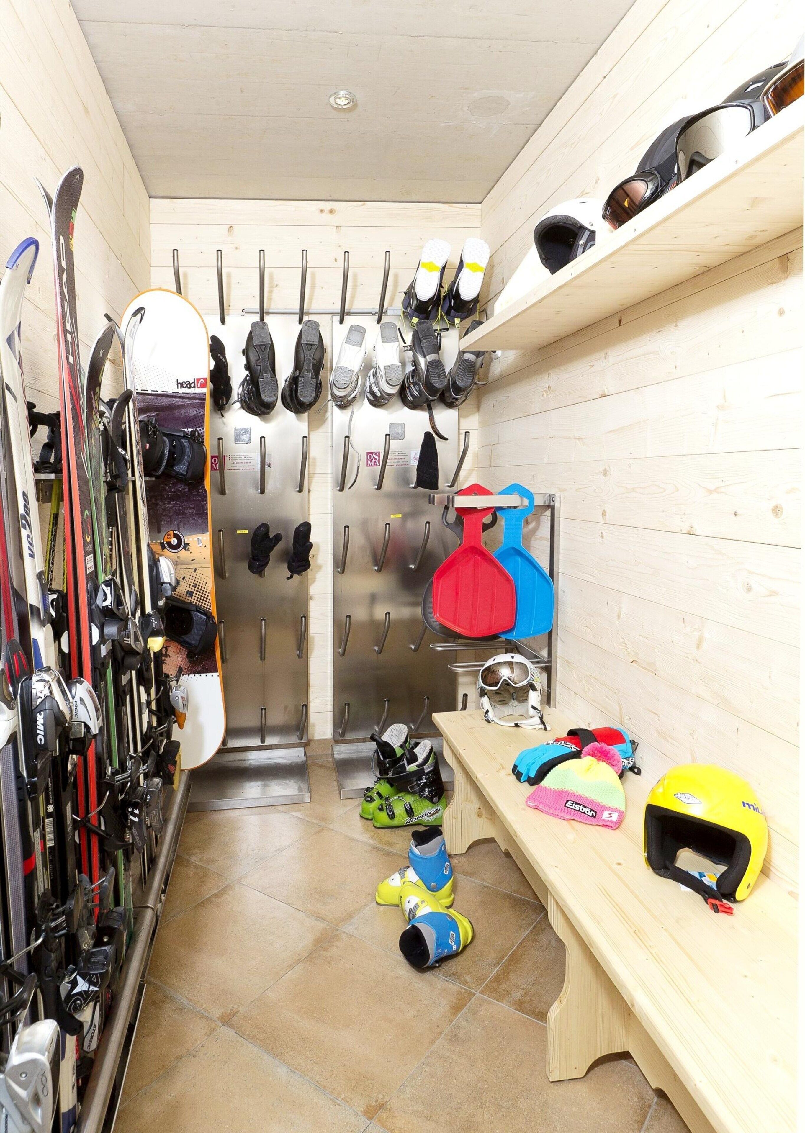 A ski storage room with skis, ski boots, and helmets.