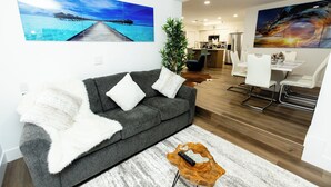 A modern living room with a grey sofa, white cushions, a wooden coffee table, and a large plant. - Your Perfect Oasis in Miami! (Miami)