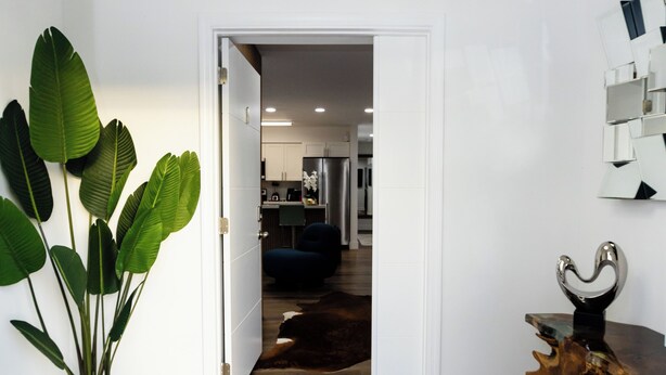 A hallway with a wooden floor, a grey rug, a potted plant, and a modern ceiling light fixture. - Your Perfect Oasis in Miami! (Miami)
