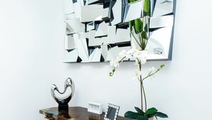 A modern interior with a wooden console table, a large abstract mirror, and a potted orchid. - Your Perfect Oasis in Miami! (Miami)